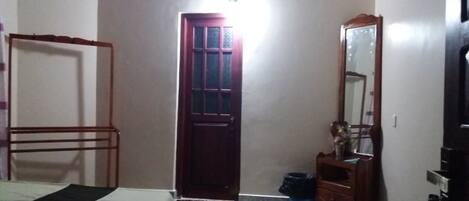 A bedroom with a bed, a wardrobe, a mirror, and a door.