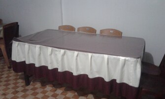 A rectangular table with a white tablecloth and a brown border, surrounded by four wooden chairs.