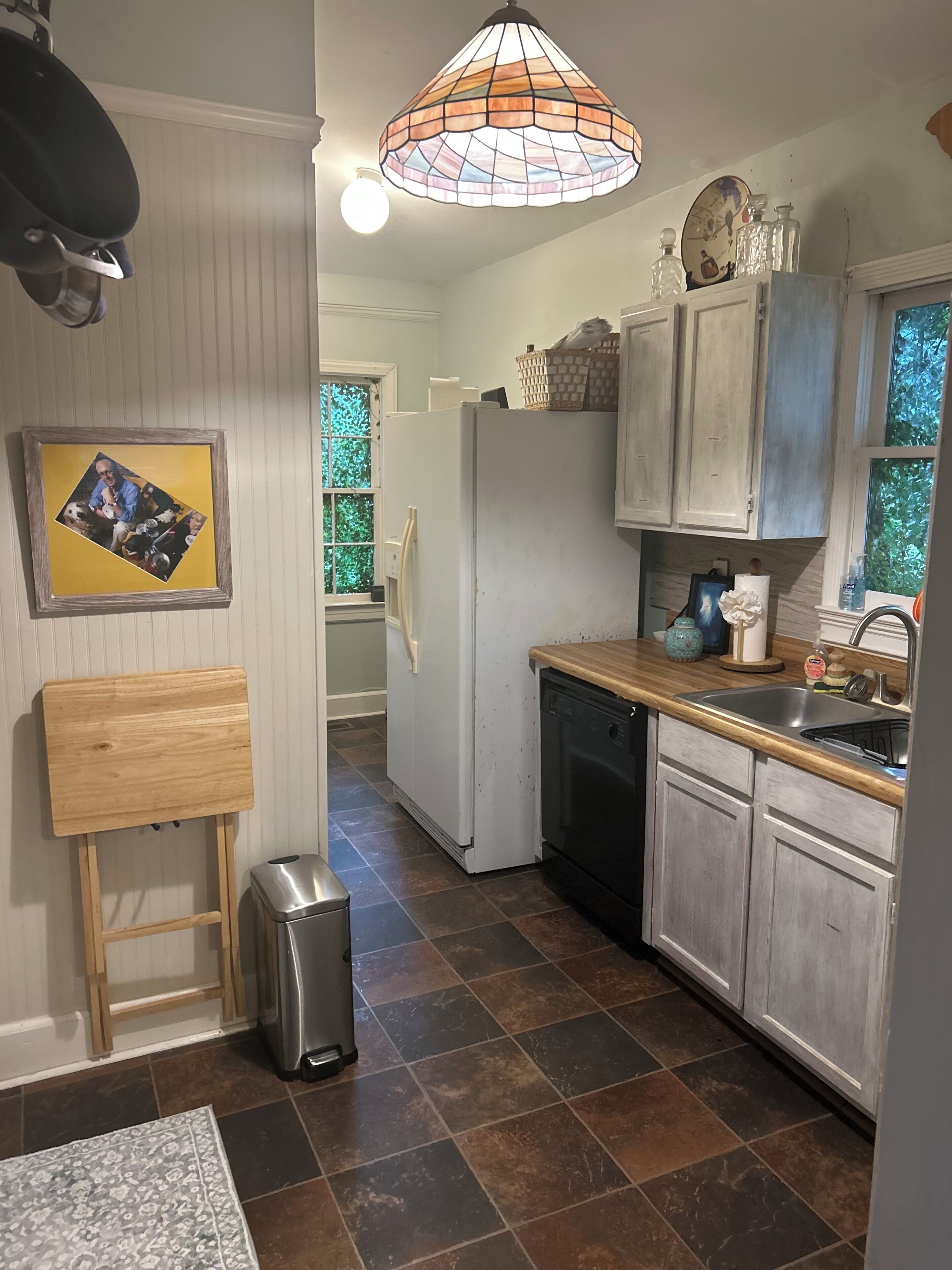 Una cocina con refrigerador, lavamanos y encimera de madera.