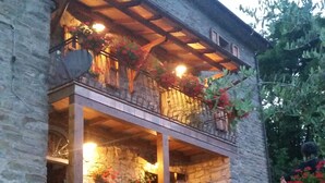 A stone building with a wooden balcony and a wooden fence. - Alla Battuta (Sansepolcro)