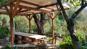 A wooden pergola with a picnic table, surrounded by trees and greenery. - Alla Battuta (Sansepolcro)