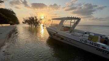 Un barco fondeado en una playa bajo un cielo despejado con atardecer.