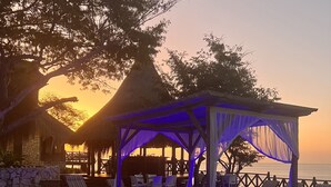 A wooden deck with a pool, lounge chairs, and a gazebo with blue lighting. - Moyeni Lodge (Vilanculos)