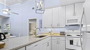 A modern kitchen with white cabinets, a built-in oven, a microwave, and a dishwasher. - Gulf Getaway – Beach Castle #12 by RVA (Longboat Key)