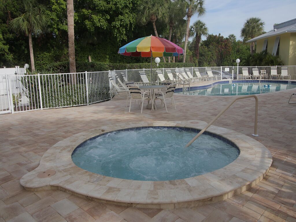 A swimming pool with lounge chairs and a hot tub.