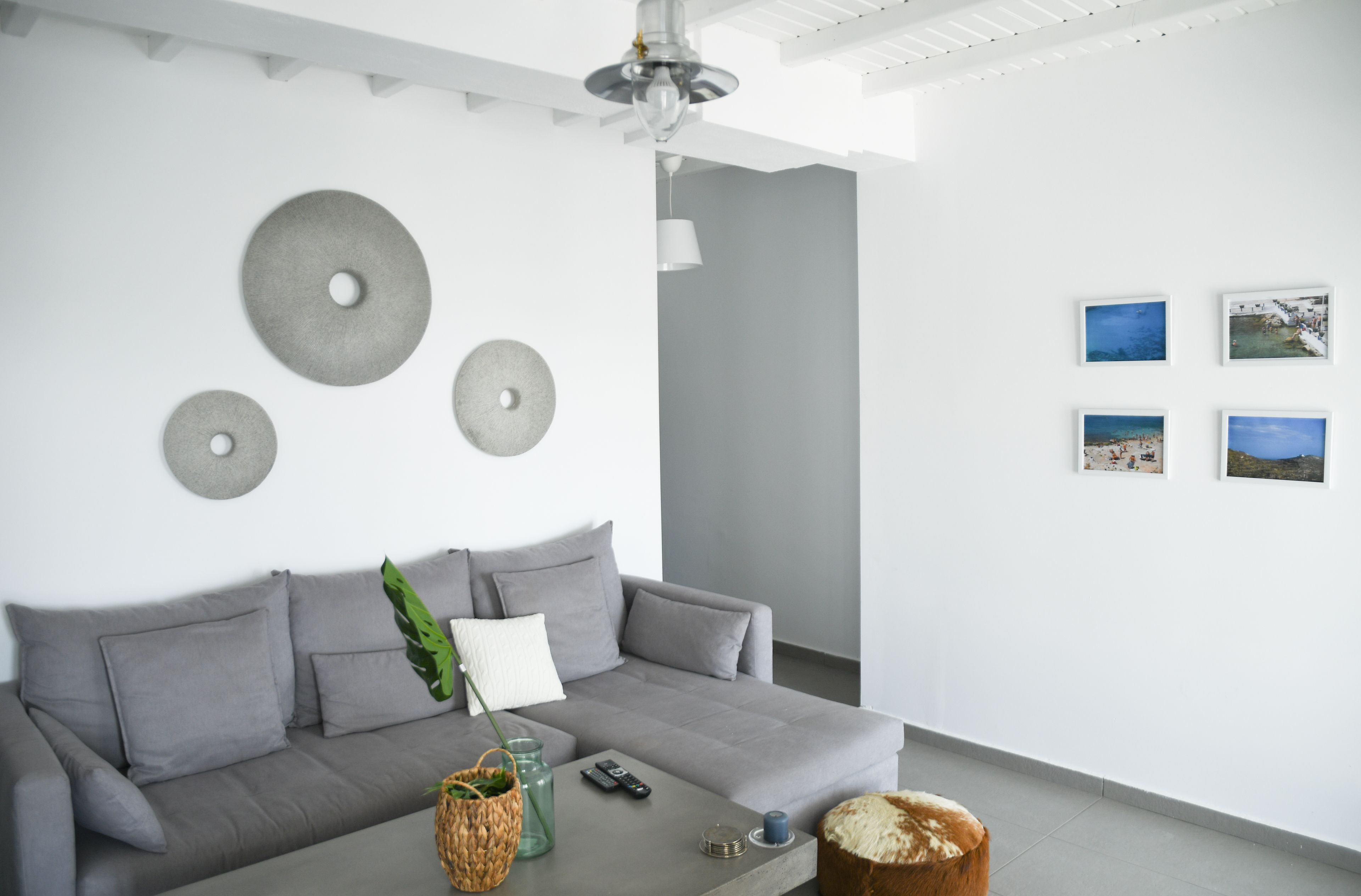 A modern living room with a grey sofa, decorative wall art, and a coffee table with a basket and remote control.