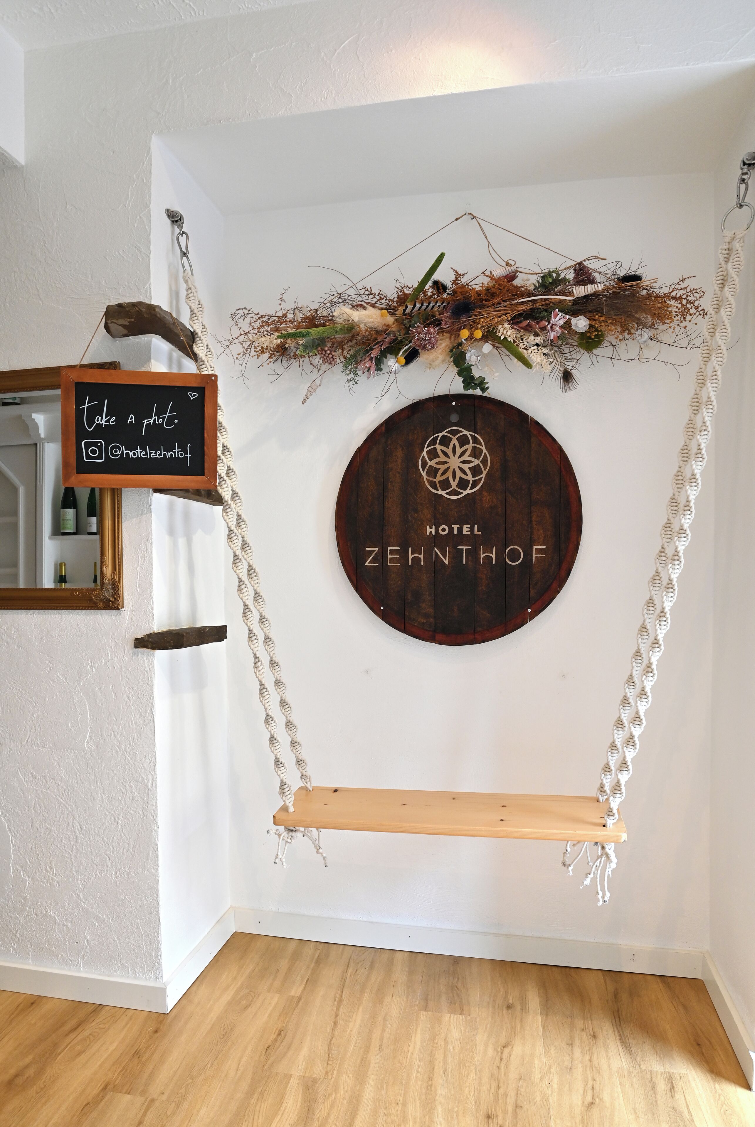 Ein an der Wand befestigtes Holzschild mit 'HOTEL ZEHNTHOF' und einem dekorativen Wandbehang mit einem Schild 'Foto machen'.