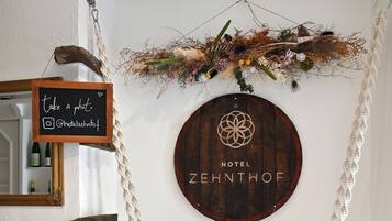 Ein an der Wand befestigtes Holzschild mit 'HOTEL ZEHNTHOF' und einem dekorativen Wandbehang mit einem Schild 'Foto machen'.