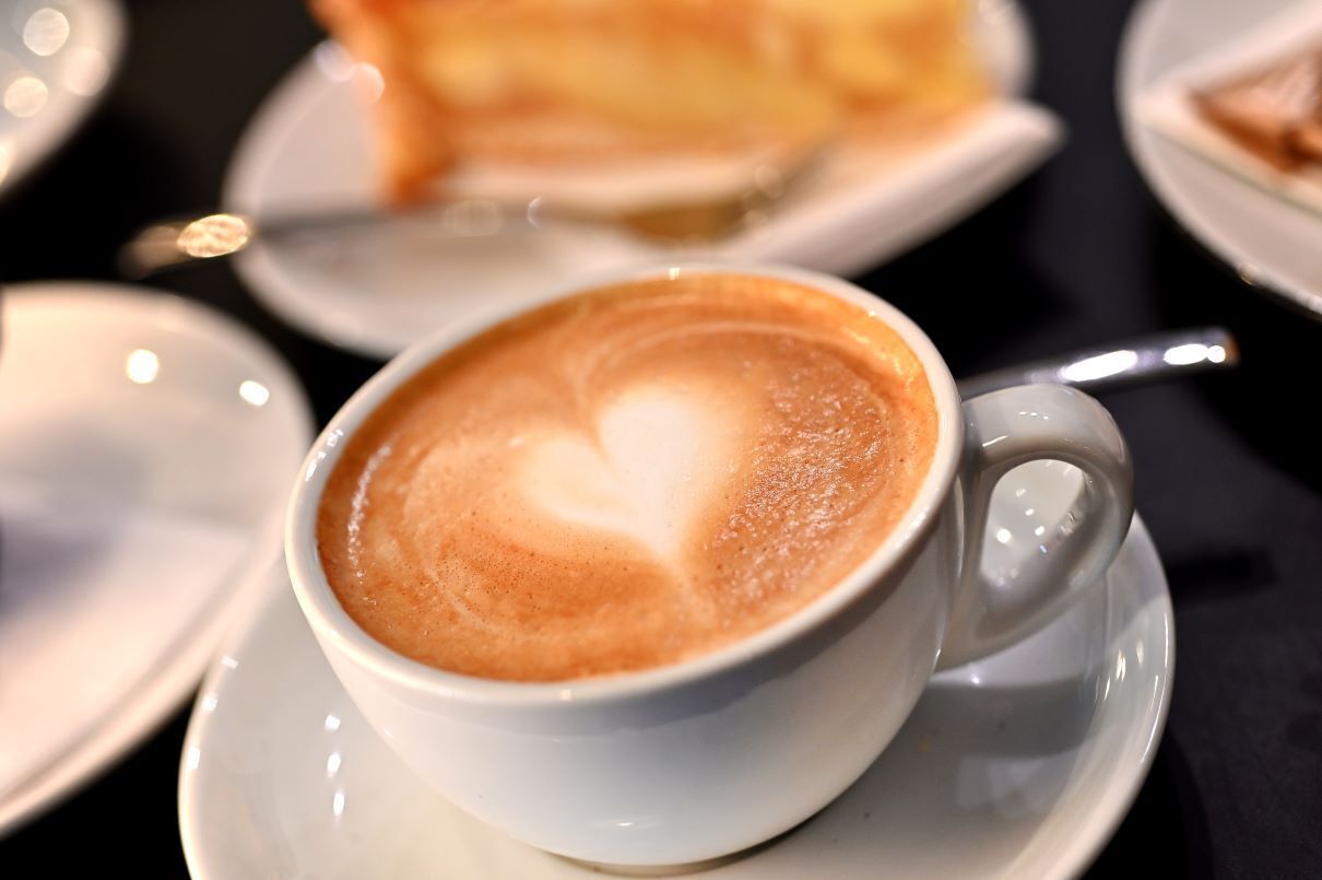 Une tasse de café sur une soucoupe, avec un motif en forme de cœur réalisé avec de la mousse de lait.