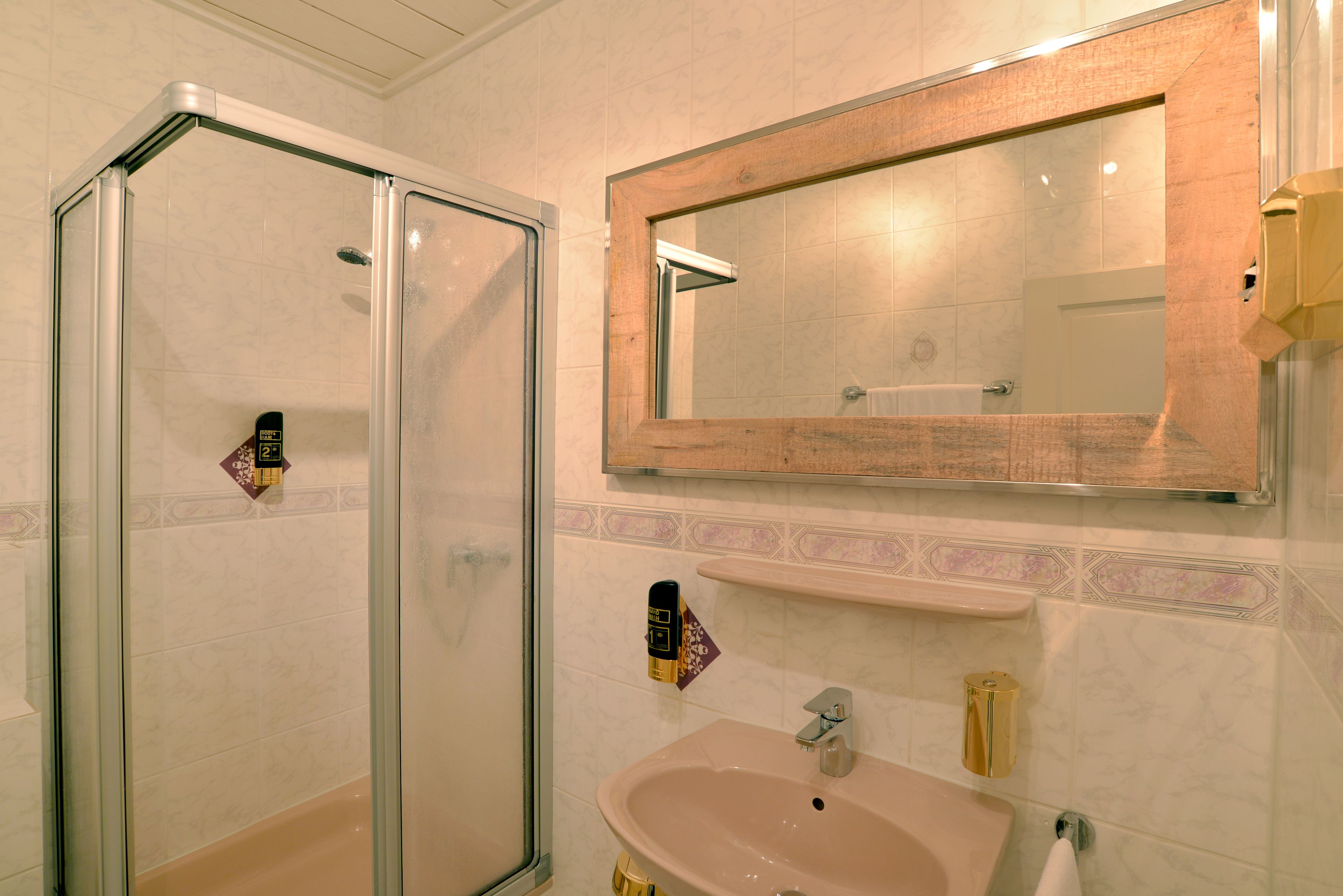 A bathroom with a glass-enclosed shower, a sink, and a mirror.