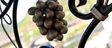 A wrought iron balcony railing with a cluster of grapes hanging from it.