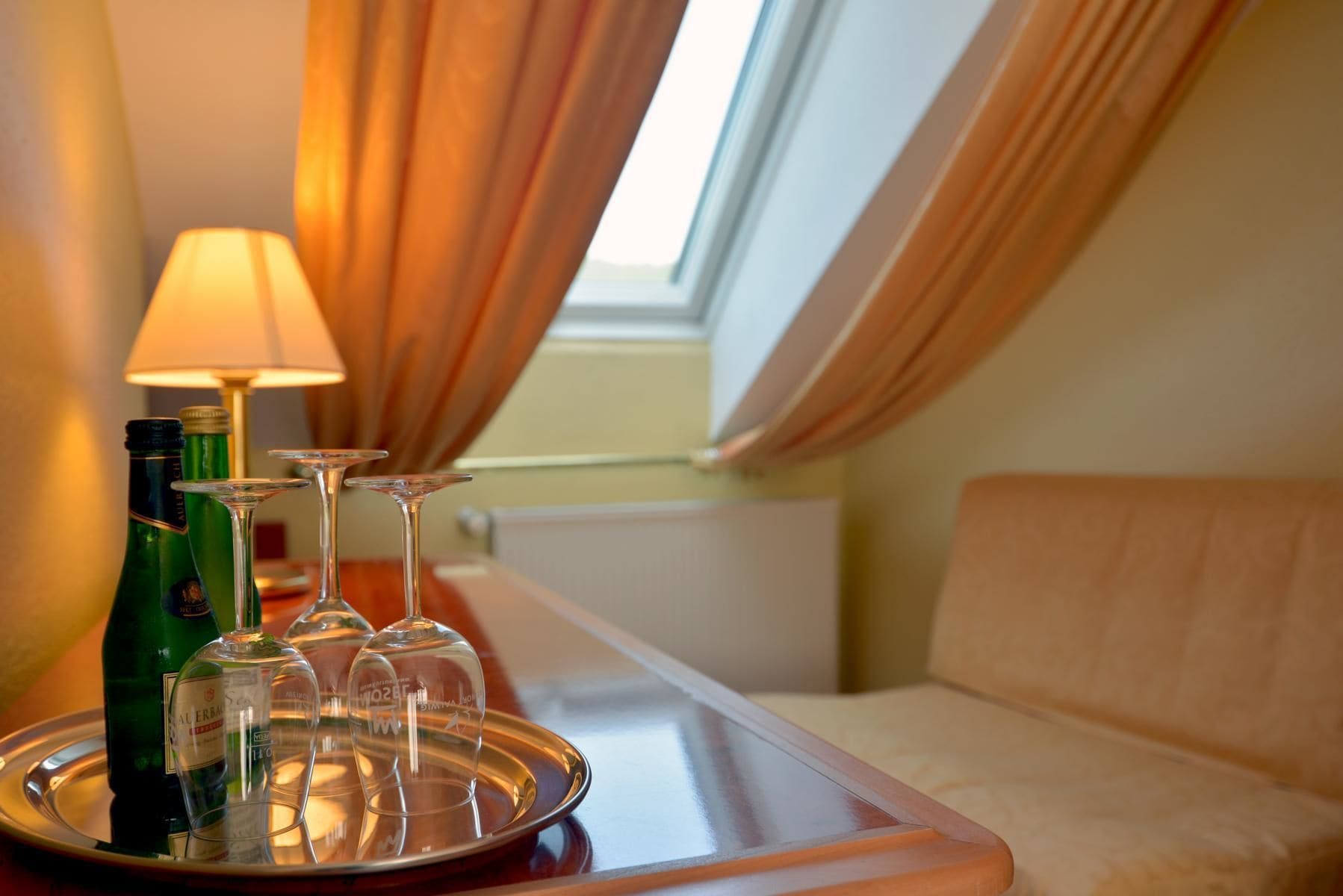 A tray with wine bottles and glasses on a table in a hotel room.