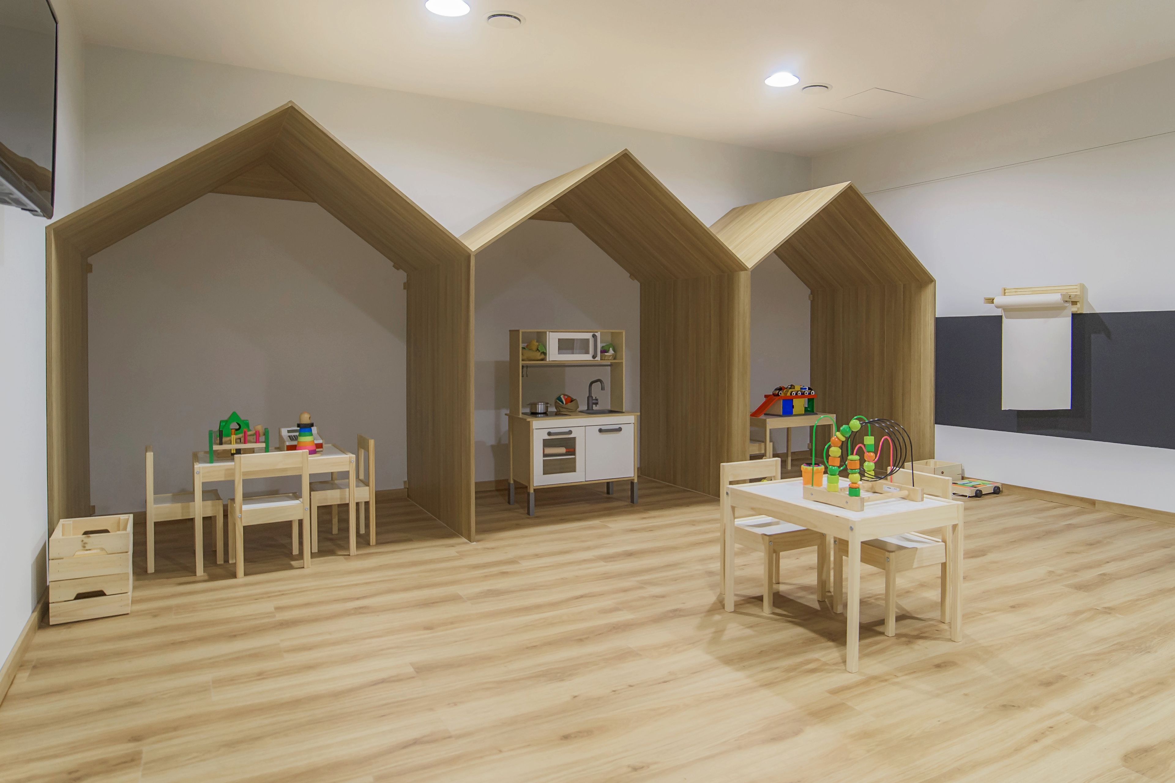Una habitación con zona de cocina, muebles de madera y una pared blanca con ventana.