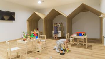 Una sala giochi per bambini con mobili in legno, una televisione e numerosi giochi.
