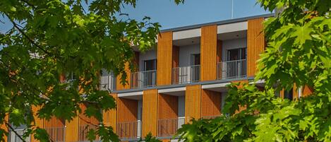 A modern building with a multi-story structure, balconies, and vertical wooden panels.