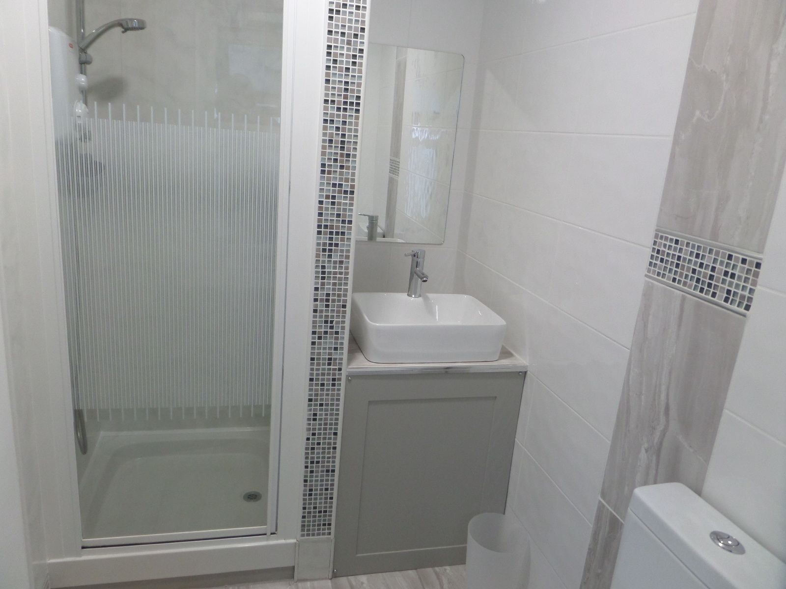 A bathroom with a glass-enclosed shower, a white sink, and a toilet.