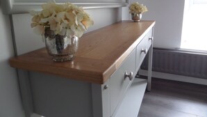 A bathroom vanity with a wooden countertop, a small vase of flowers, and a mirror above it.
