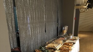 Ett buffébord med olika sorters mat och dryck, inklusive frukt, bakverk och kaffe.