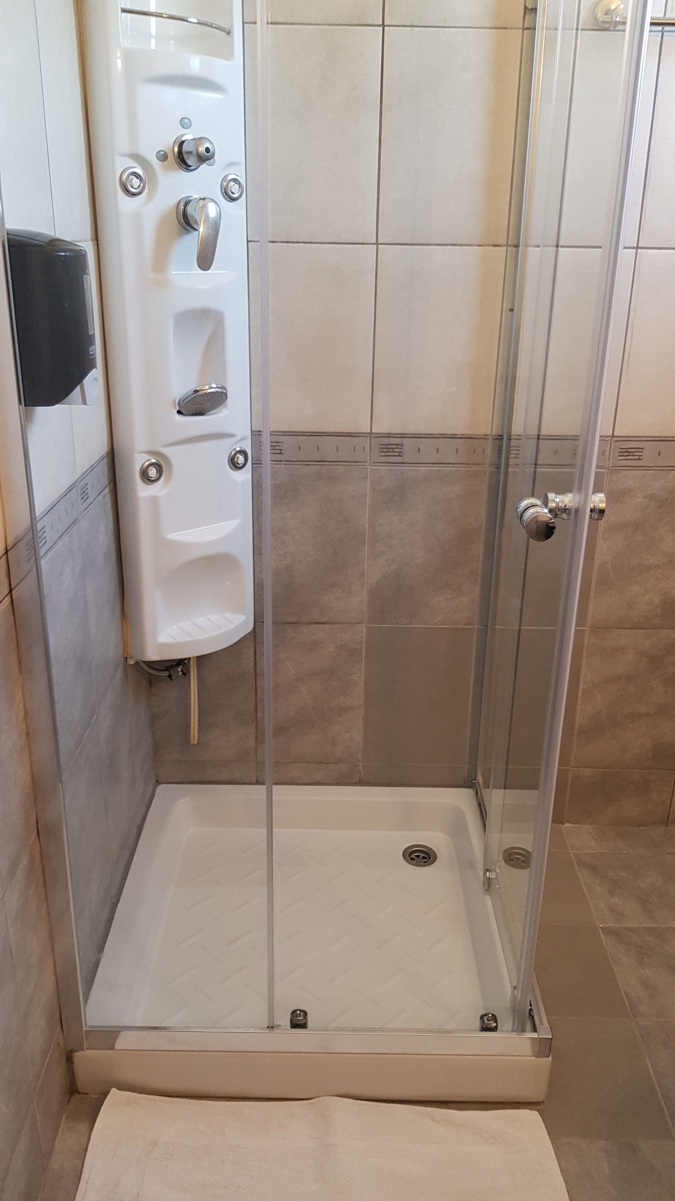 Une cabine de douche avec une porte en verre, un sèche-mains et un porte-serviettes.