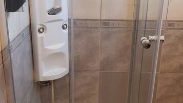 Une cabine de douche avec une porte en verre, un sèche-mains et un porte-serviettes.