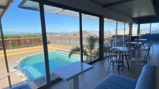 En rymlig balkong med pool, stora fönster och blå sittmöbler.