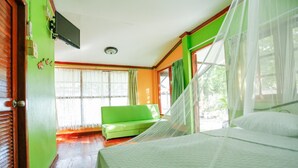 A room with a bed, a green sofa, a television on the wall, and a window with curtains. - Kasemsuk Resort (Bang Saphan)