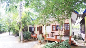 A bungalow with a porch, surrounded by trees and plants. - Kasemsuk Resort (Bang Saphan)