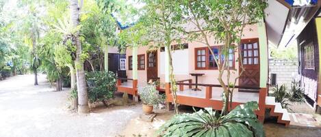 Una cabaña con porche, rodeada de árboles y plantas.