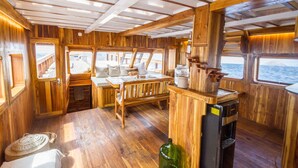 Ein Holzblockhaus-Innenraum mit Essbereich, einer kleinen Küche und großen Fenstern.