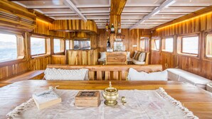Eine Holzhütte mit einem großen Tisch, einer Decke, Kissen und einem Buch.