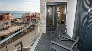 Een balkon met uitzicht op zee, een glazen deur en een metalen hekwerk.
