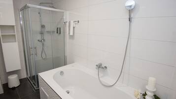 Un baño moderno con ducha envuelta en vidrio, una bañera grande y un inodoro.