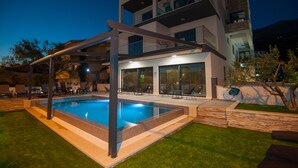 Un edificio moderno con piscina, mobiliario exterior y un patio cubierto.