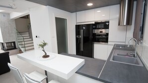 Una cocina moderna con armarios blancos, electrodomésticos de acero inoxidable y una isla central con espacio para sentarse.