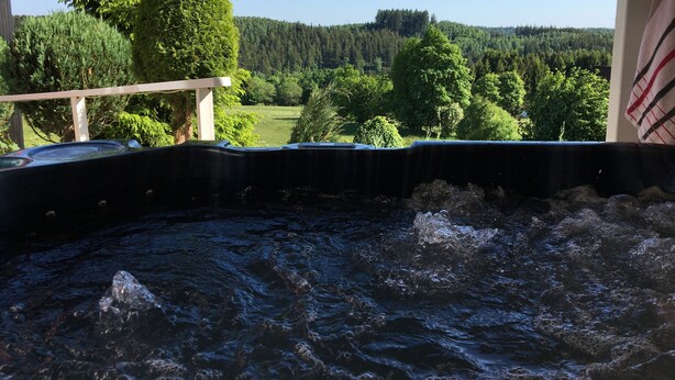 A hot tub with a wooden deck and a view of a forested landscape. - Harmonie Hotel Rust (Braunlage)