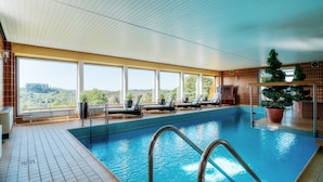 An indoor swimming pool with clear views of a forested landscape through large windows. - Harmonie Hotel Rust (Braunlage)
