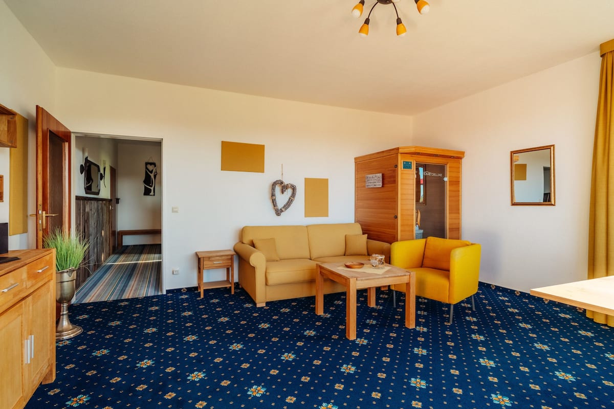Ein Wohnzimmer mit einer Couch, einem gelben Sessel, einer Holzkommode und einem kleinen Tisch.