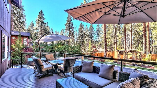 A deck with outdoor furniture, including a sofa and chairs, and a large umbrella providing shade. - Zephyr Cove Versailles Private Beach & Ski Permitted DSTR1077P NV vacation House (Glenbrook)