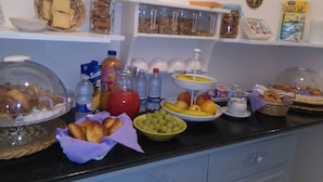 A buffet with various food items and beverages, including bread, pastries, fruits, and drinks.