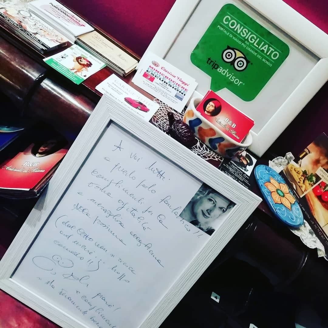 A desk with various items including a framed handwritten note, a green card, and several books.