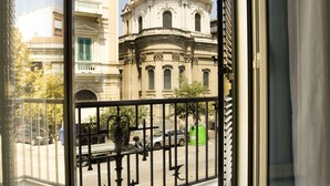 A balcony with a view of a historic building with a dome and columns.