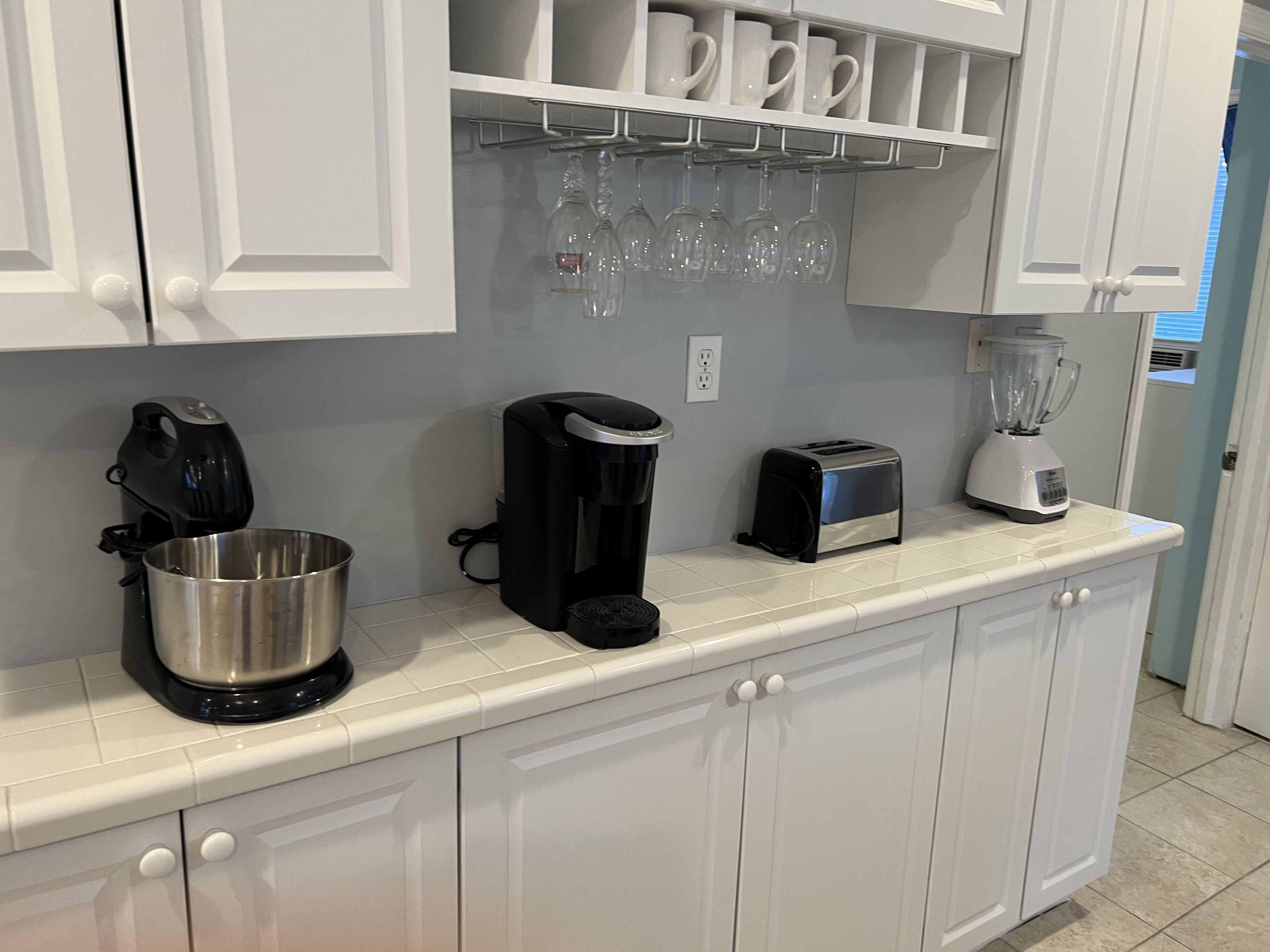 A kitchen with white cabinets, a coffee maker, a toaster, and a blender on the countertop.