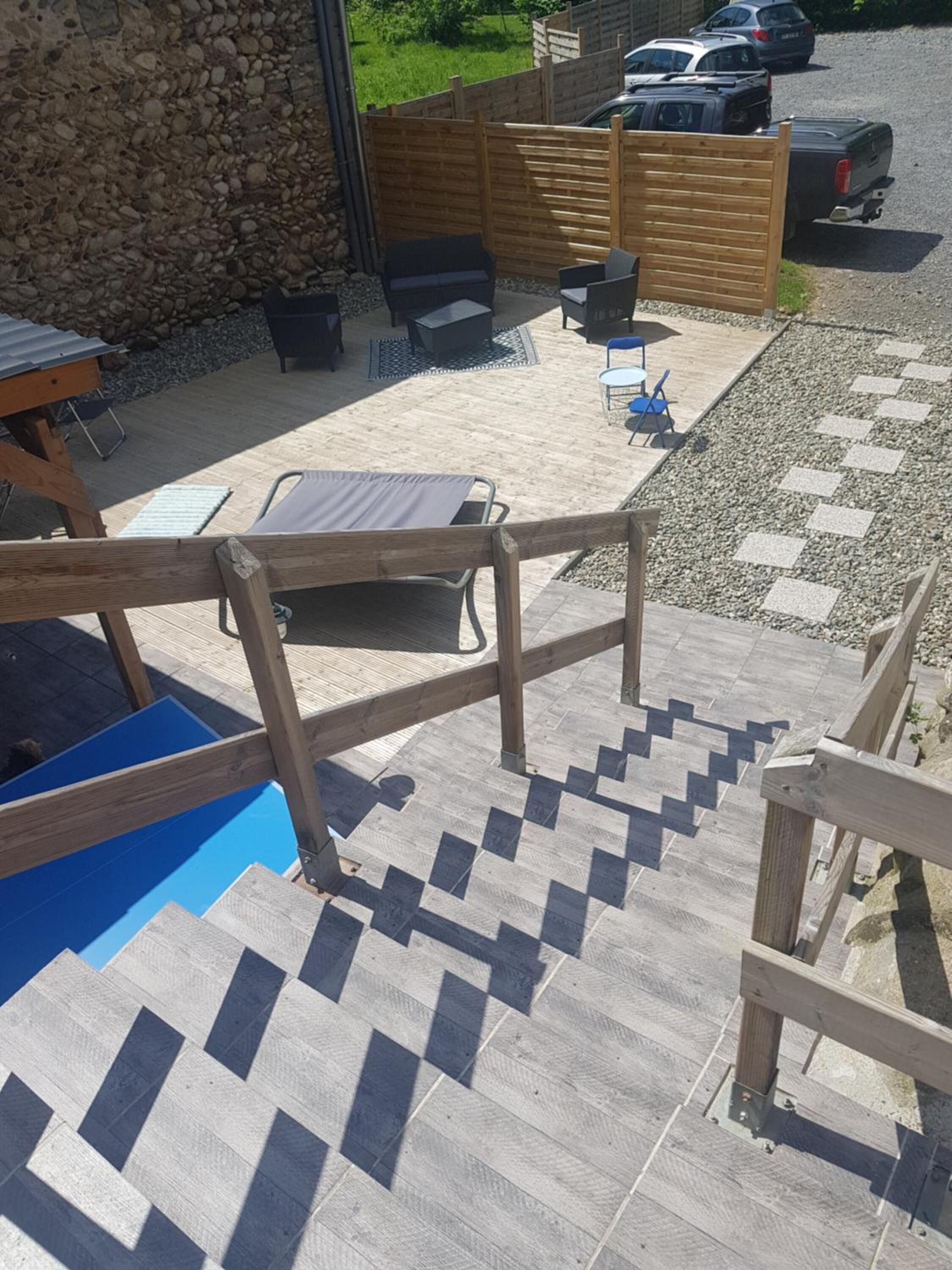 A patio area with outdoor furniture, a wooden fence, and a gravel path.
