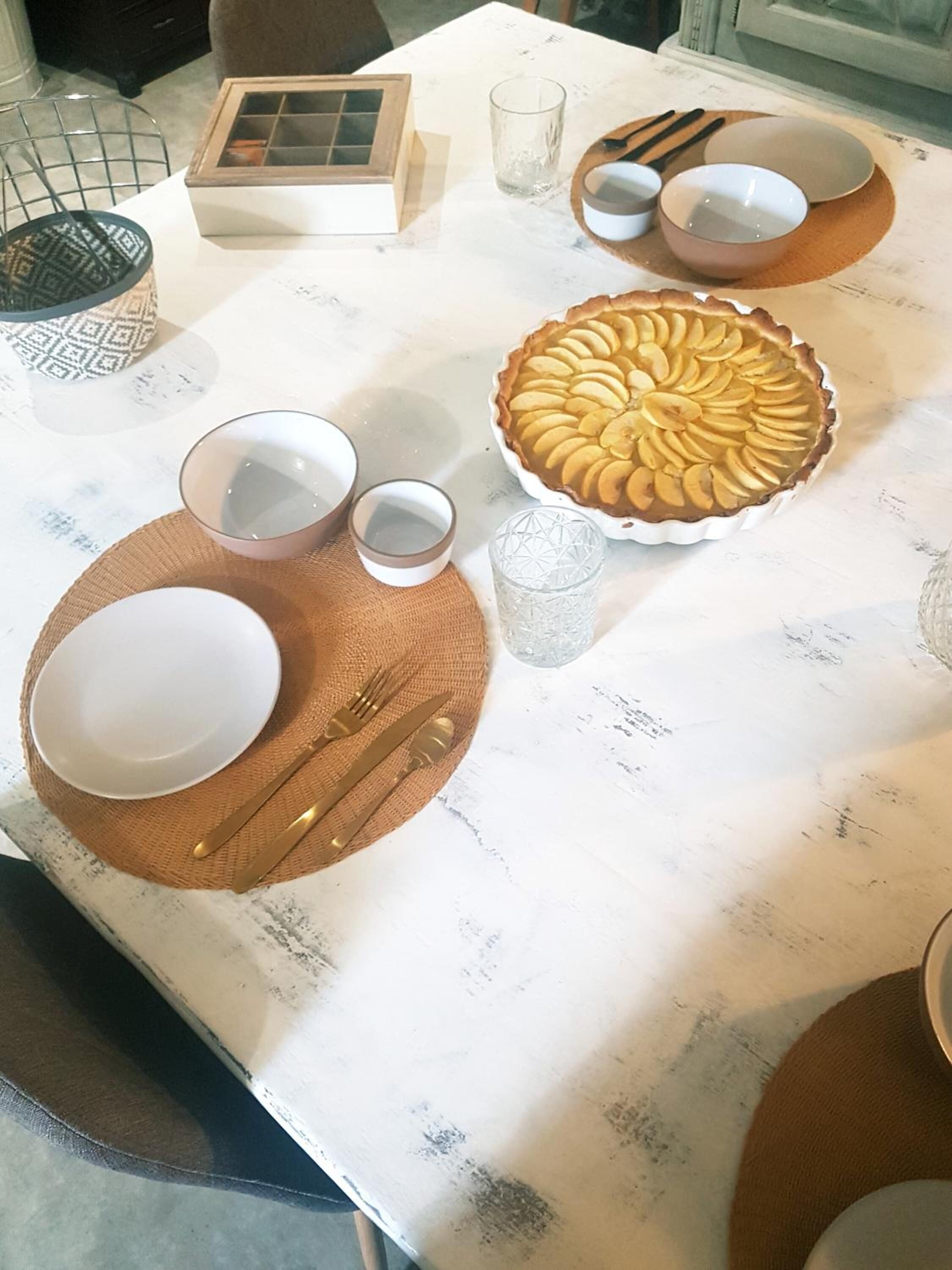 A dining table set with a pie, bowls, and cutlery.