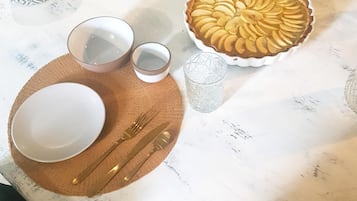 A dining table set with a pie, bowls, and cutlery.