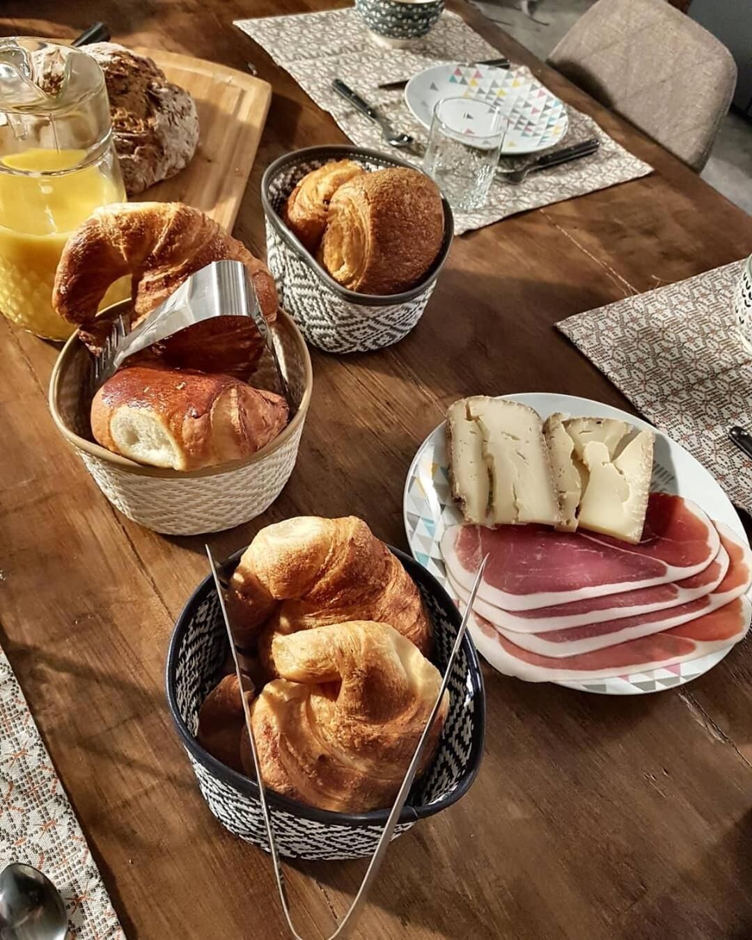 Ett frukostbord med croissanter, ost och skinka.