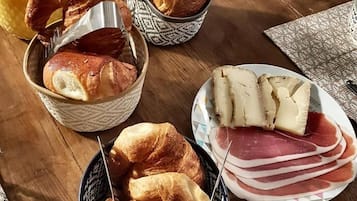 Ett frukostbord med croissanter, ost och skinka.
