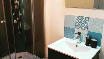 A bathroom with a glass-enclosed shower, a white sink with a modern faucet, and a tiled backsplash.