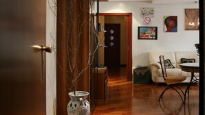 A hallway with wooden flooring, a vase, and a door. - Stupor Mundi (Altamura)