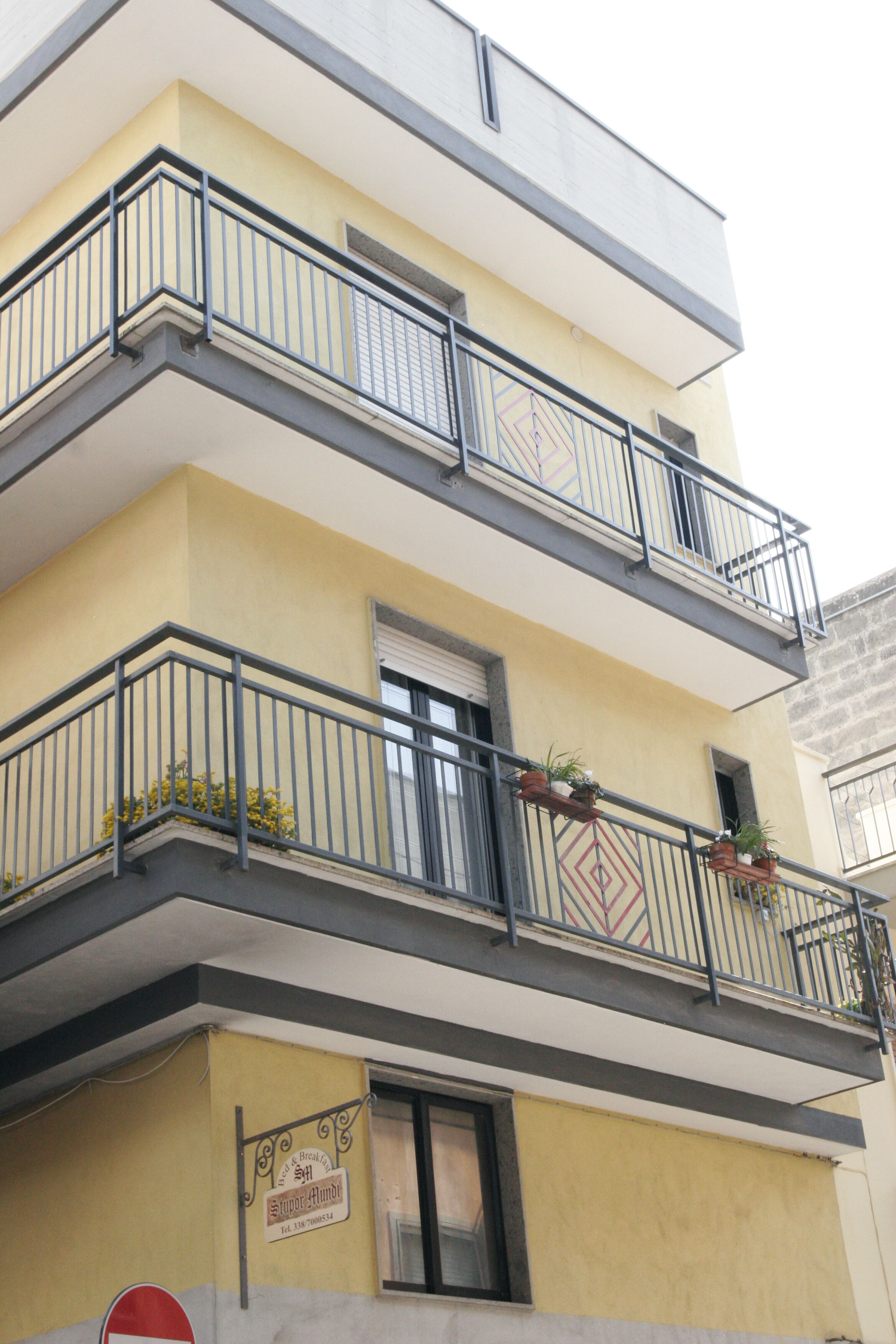 Un edificio de varios pisos con balcones, una puerta y un cartel en la pared.
